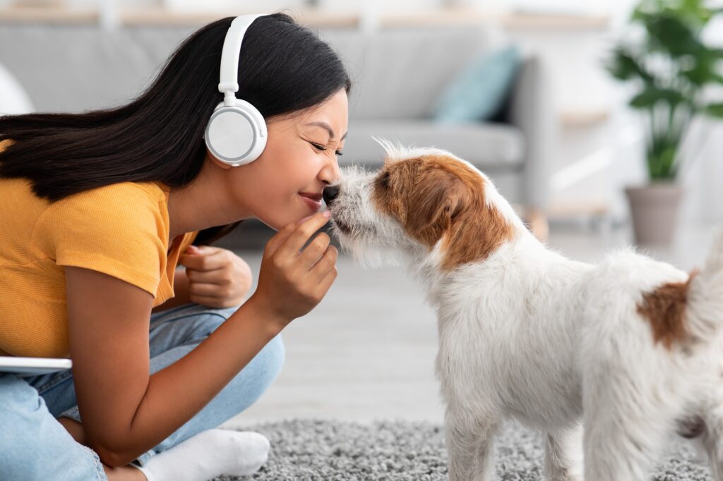 Loving asian woman cuddling with her pet at home